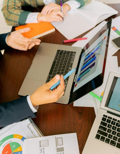 A productive workspace with colleagues discussing data charts and using laptops for business collaboration.